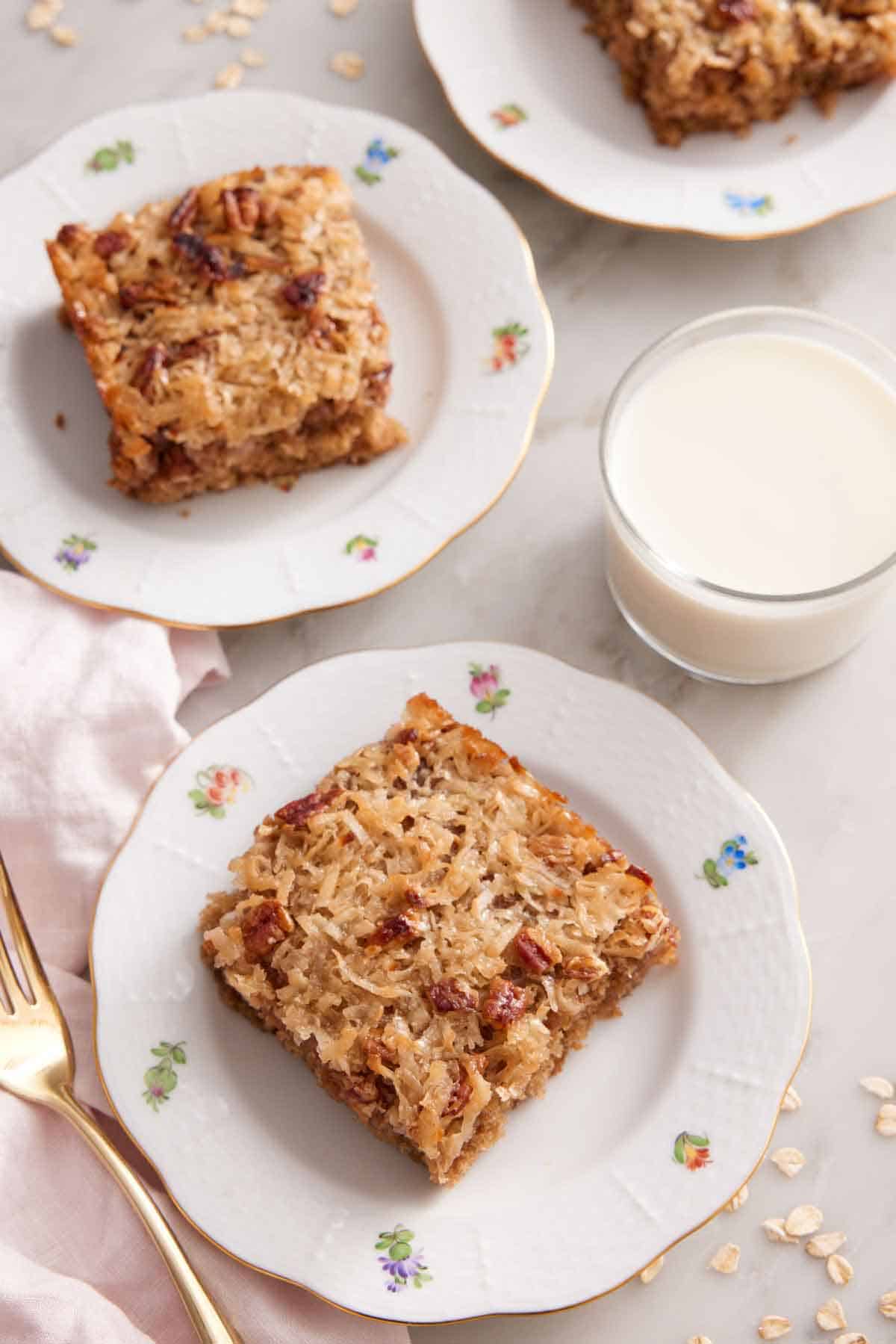 Overhead view of two plates of oatmeal cake with a glass of milk.