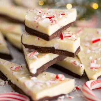 A stack of peppermint bark surrounded by candy canes and bits of crushed candy canes.