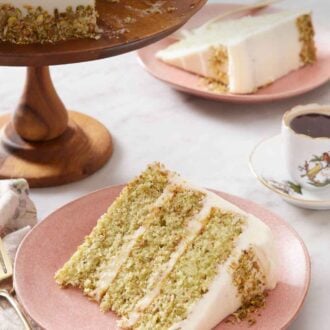 Pinterest graphic of a slice of pistachio cake on a plate with the cake on a cake stand in the back along with a coffee and second plated slice.