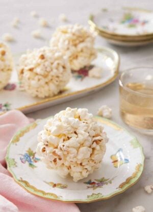 A popcorn ball on a plate with more balls in the background on a platter.