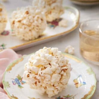 Pinterest graphic of a popcorn ball on a plate with more balls in the background on a platter.