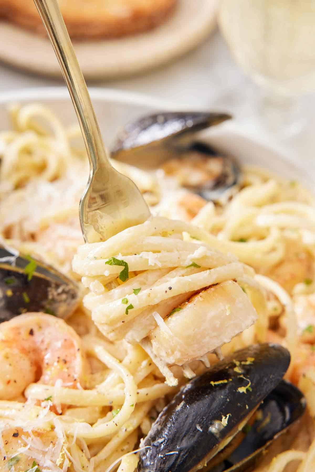 A forkful of seafood pasta lifted from a plate.