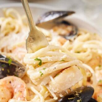 Pinterest graphic of a fork with seafood pasta twirled around it and lifted from a plate.