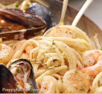 Pinterest graphic of a close view of seafood pasta in a skillet with a fork inserted.