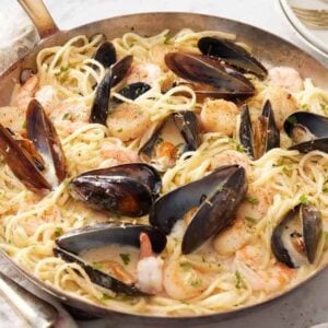 A skillet of seafood pasta topped with chopped parsley.