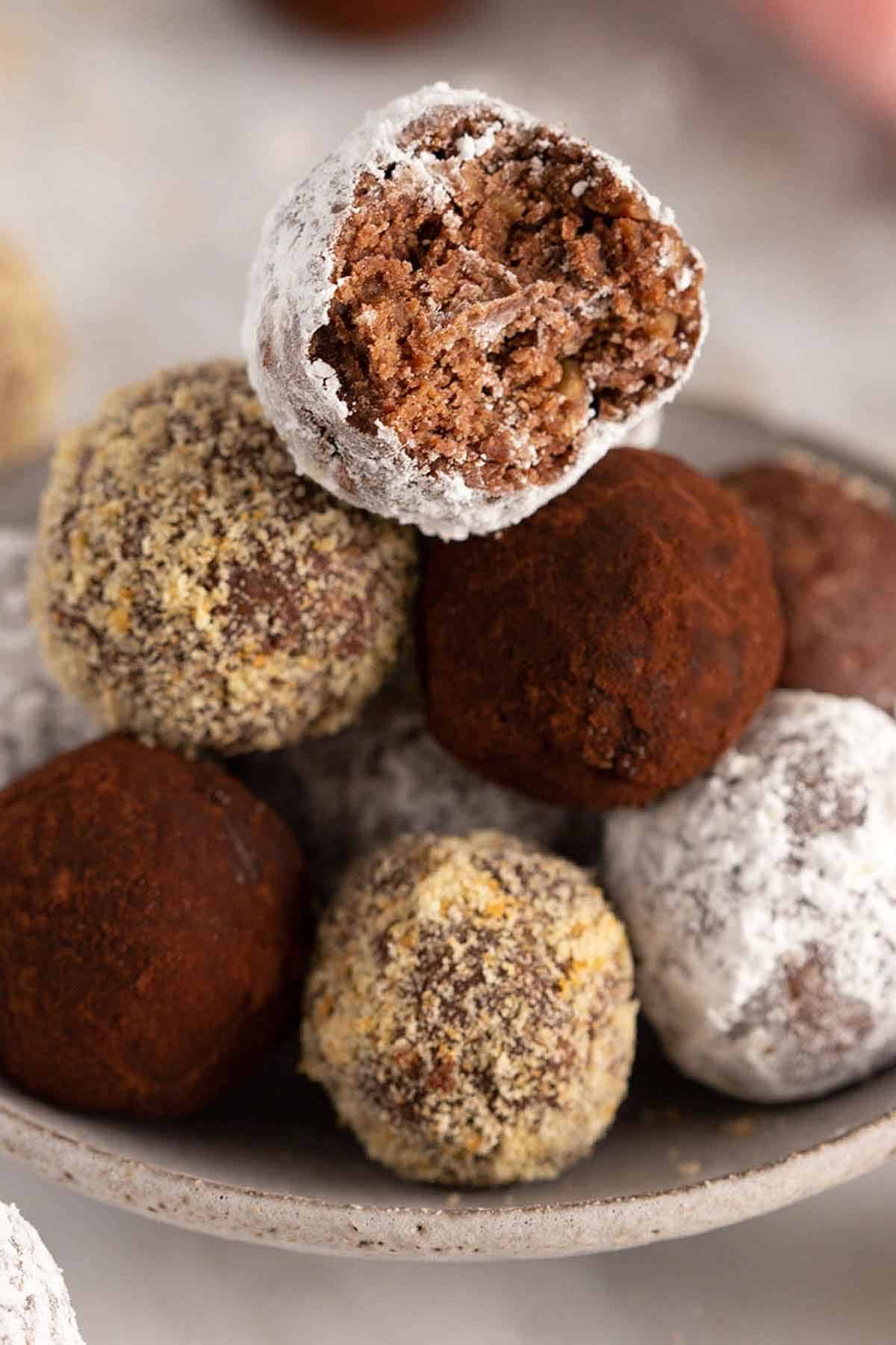A pile of rum balls with the one on top with a bite taken out of it.