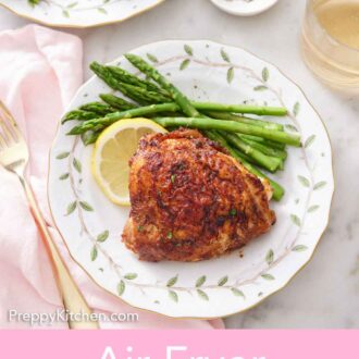 Pinterest graphic of an overhead view of a plate of air fryer chicken thigh with a lemon slice and asparagus.