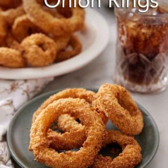 Pinterest graphic of a plate of air fryer onion rings with a platter more in the back along with a glass of soda.