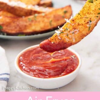Pinterest graphic of an air fryer potato wedge dipped into a bowl of ketchup.