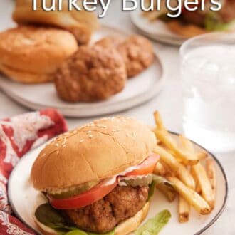 Pinterest graphic of a plate of air fryer turkey burger with fries on the side with a glass of water in the background along with more burger ingredients.