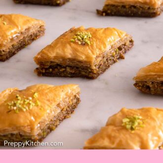Pinterest graphic of multiple pieces of baklava in a single layer spread on a counter.