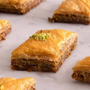 Multiple pieces of baklava in a single layer spread on a counter.