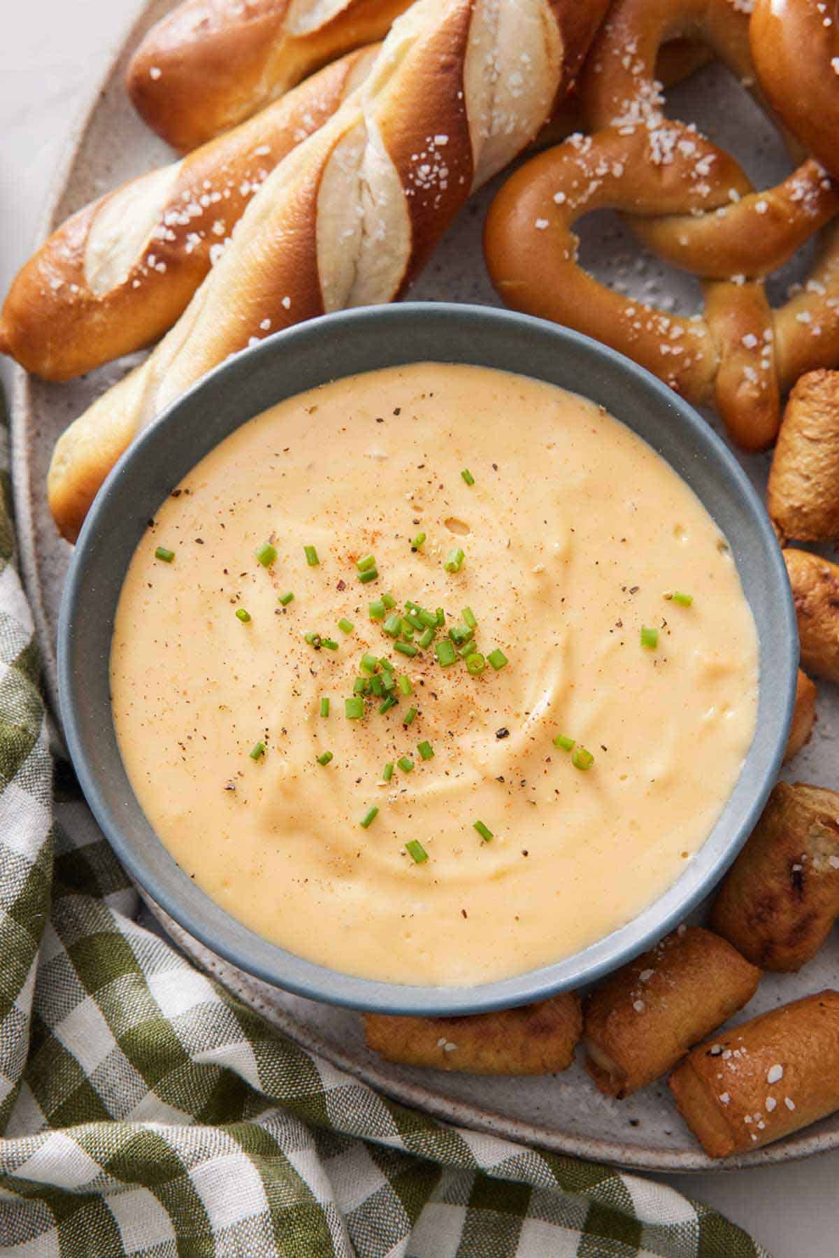 Overhead view of a bowl of beer cheese dip surrounded by pretzels.