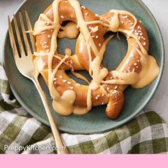 Pinterest graphic of a pretzel on a plate with a fork with beer cheese dip drizzle over top.