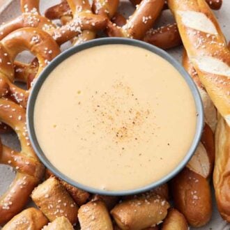 Overhead view of beer cheese dip surrounded by different types of pretzels.
