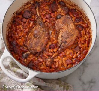 Pinterest graphic of a pot with cassoulet with torn bread in the background.