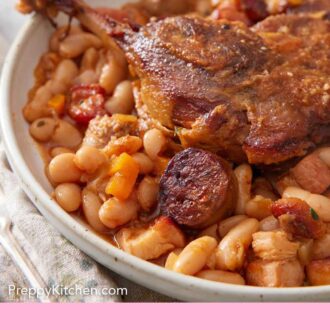 Pinterest graphic of a close up view of cassoulet on a plate.