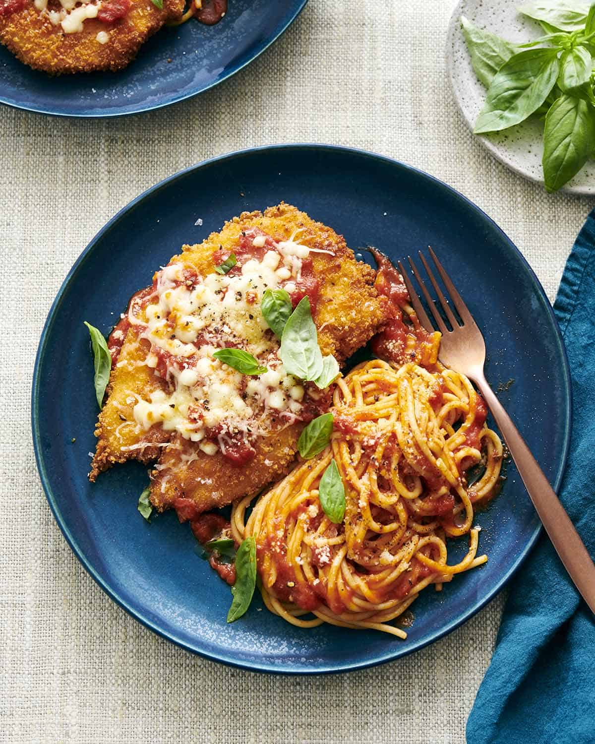 A photo of chicken parmesan with spaghetti on a blue plate.