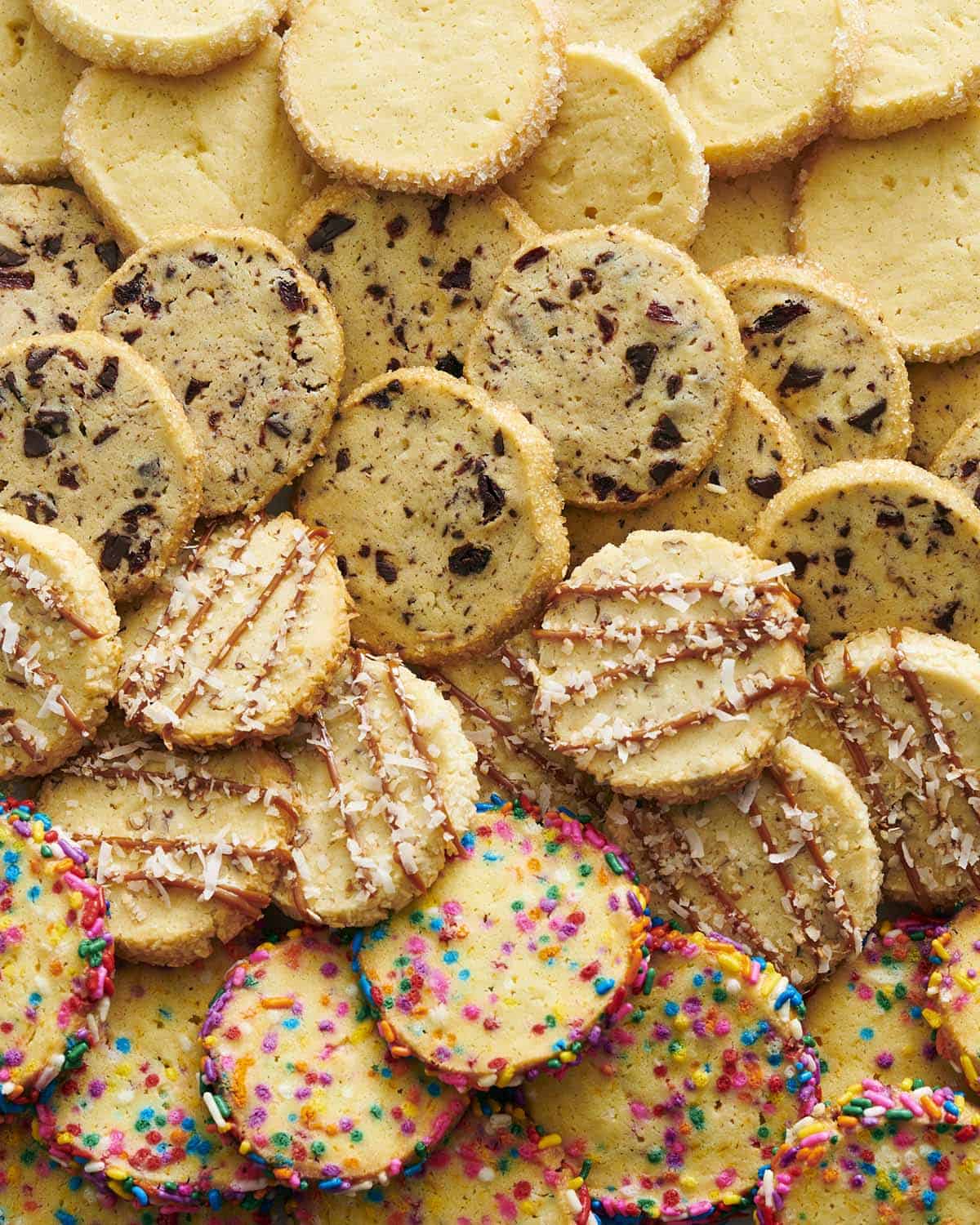A photo of shortbread cookies, plain, with chocolate chips, caramel and sprinkles.