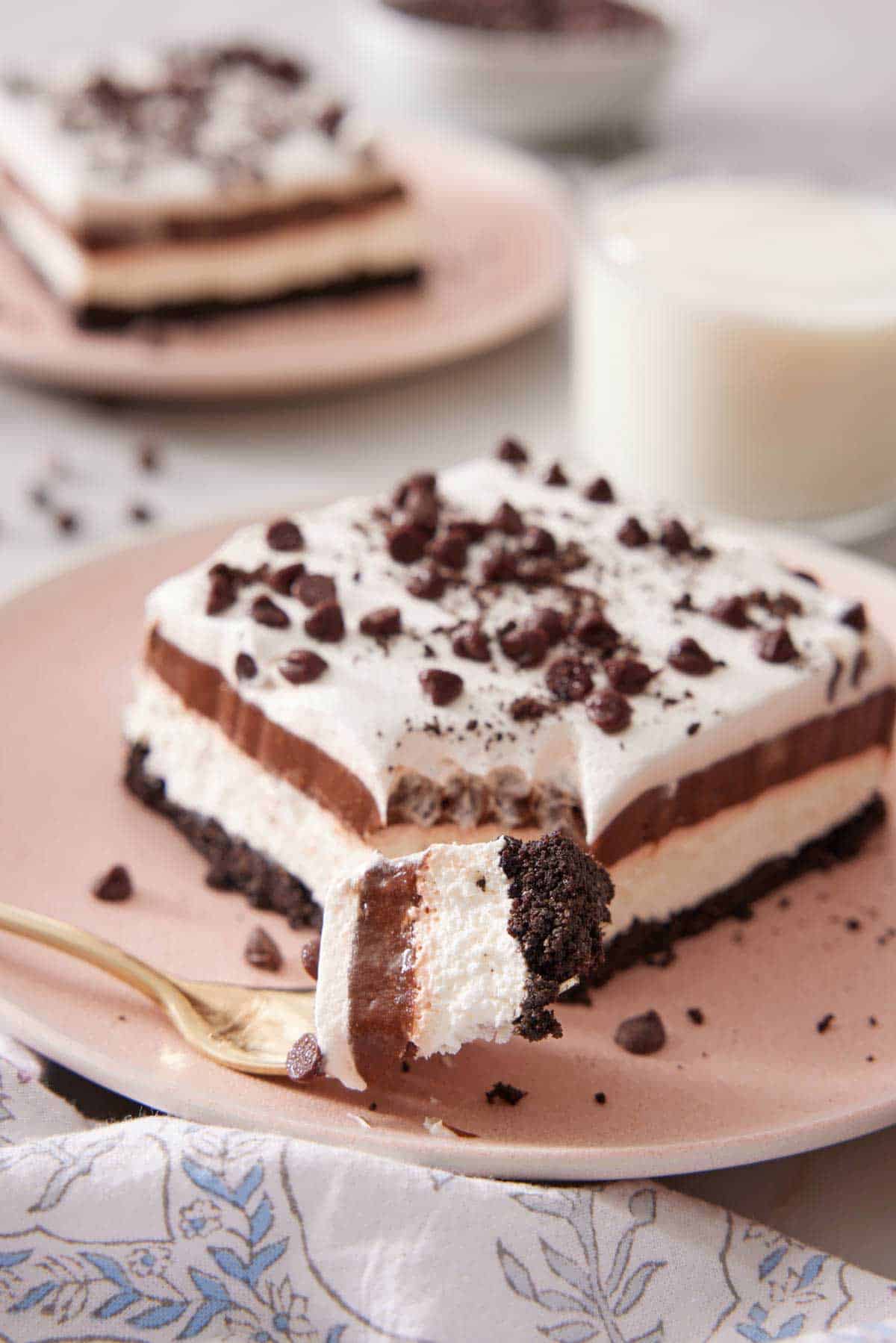 A plate with a slice of chocolate lasagna with a fork in front with the corner bite on it.