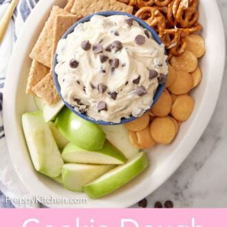 Pinterest graphic of an overhead view of a platter with a bowl of cookie dough dip surrounded by crackers, pretzels, and sliced apples.