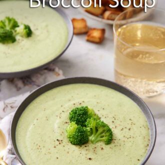 Pinterest graphic of two bowls of cream of broccoli soup with one front. Both bowls topped with fresh broccoli florets and pepper. A glass of wine in the back with croutons.