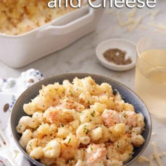 Pinterest graphic of a bowl of lobster mac and cheese with a baking dish with more in the background along with a drink and bowl of pepper.