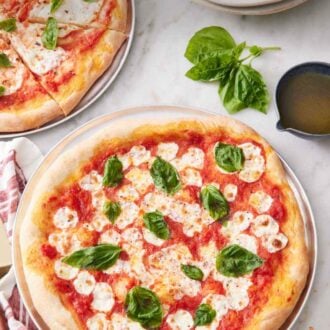 Pinterest graphic of a margherita pizza topped with fresh basil leaves with a second sliced pizza in the background along with a stack of plates and forks.