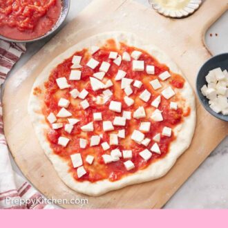 Pinterest graphic of margherita pizza on a wooden board before being baked.