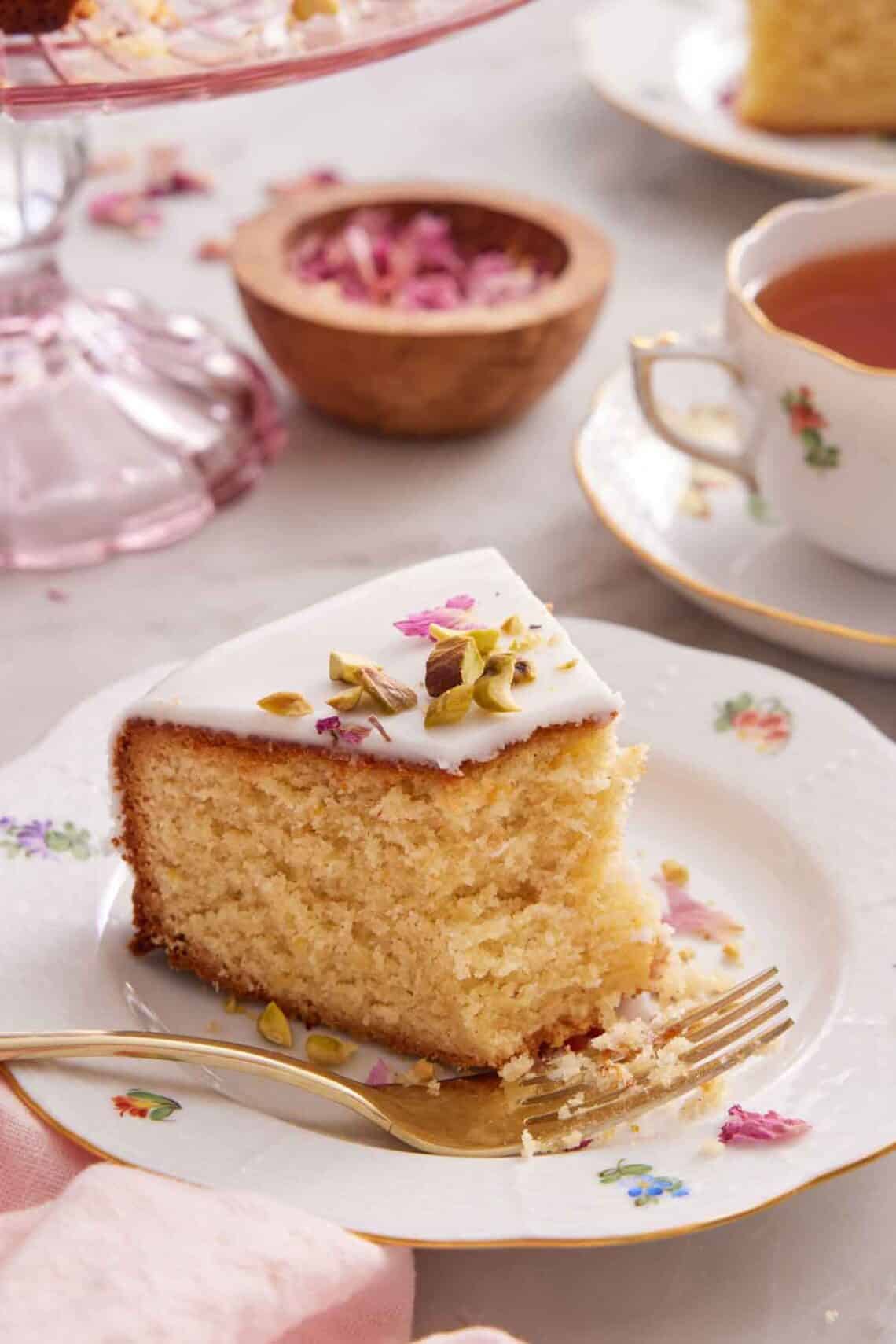 A plate with a slice of Persian love cake with half of it eaten and a fork on the plate.