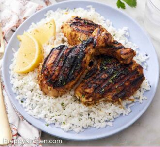 Pinterest graphic of a plate with tandoori chicken over a bed of rice with lemon wedges.