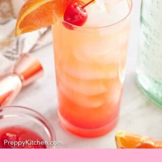 Pinterest graphic of a tequila sunrise cocktail with orange slice and maraschino cherry garnish. A jiggle, some garnishes, and a bottle of tequila in the back.