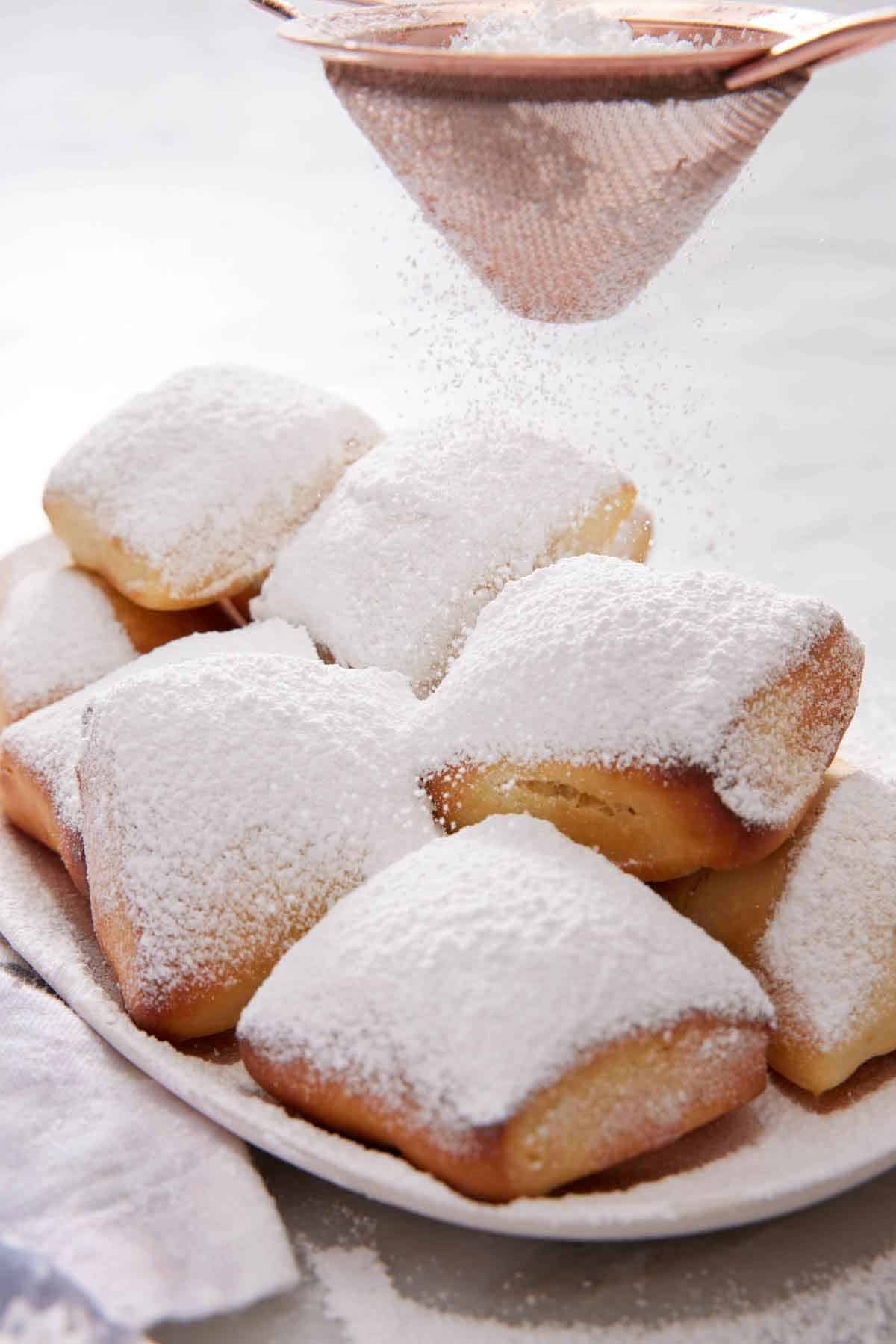 Powdered sugar dusted over a platter of air fryer beignets.