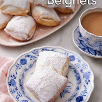 Pinterest graphic of a plate with two air fryer beignets with a platter in the background along with a cup of coffee.