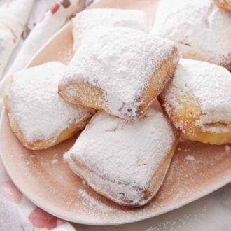 A platter of air fryer beignets with a dusting of powder sugar on top.