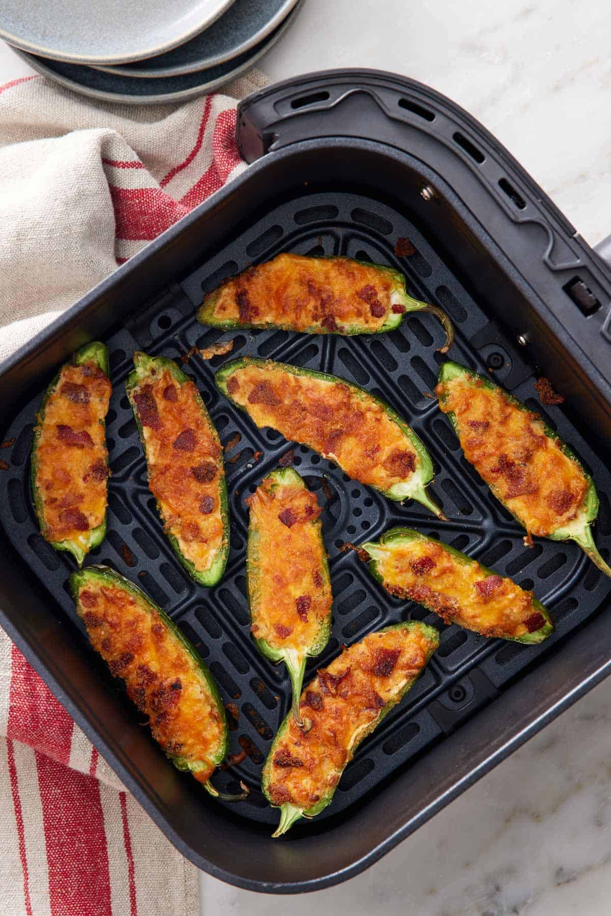 Overhead view of jalapeno poppers in an air fryer basket.