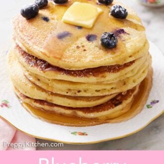 Pinterest graphic of a stack of blueberry pancakes with blueberries, butter, and maple syrup on top with a dusting of powdered sugar.