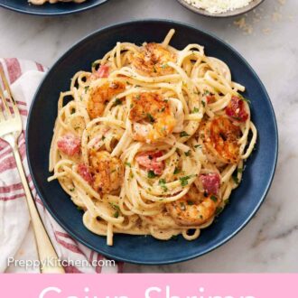 Pinterest graphic of a plate of cajun shrimp pasta with a bowl of shredded parmesan on the side and a second serving of pasta off to the side.