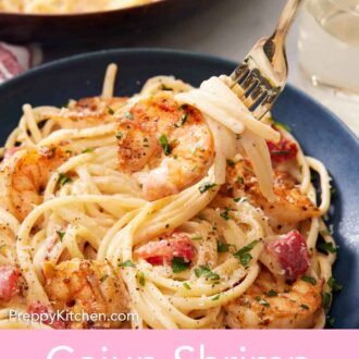 Pinterest graphic of a fork lifting up a bite of cajun shrimp pasta from a bowl.