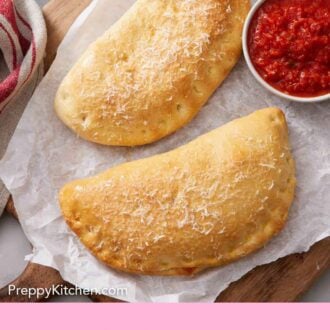 Pinterest graphic of an overhead view of two calzones on a sheet of parchment over a wooden serving board with a bowl of pizza sauce.
