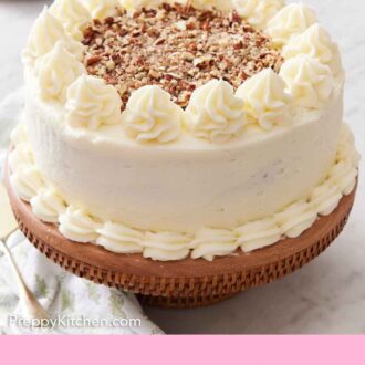 Pinterest graphic of a carrot cake coated in frosting and topped with chopped pecans on a cake stand.