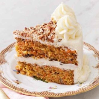 A slice of carrot cake on a plate with a fork beside it.