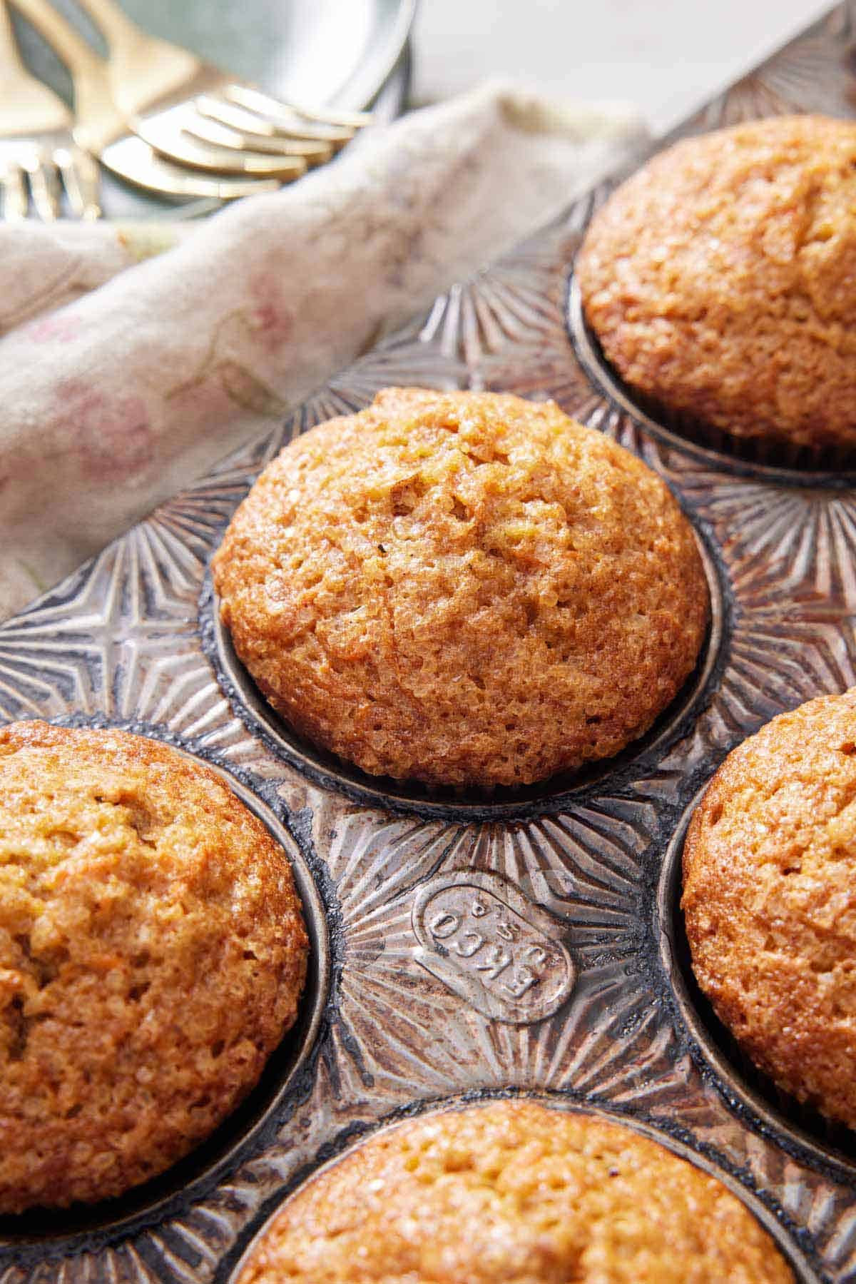 Carrot muffins in a muffin tin. Forks in the background.