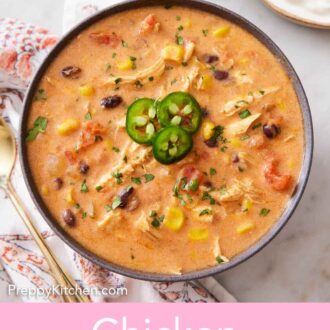 Pinterest graphic of a bowl of enchilada soup topped with three sliced jalapenos and chopped cilantro.