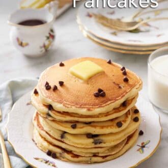 Pinterest graphic of a stack of chocolate chip pancakes with butter on top with a few extra chocolate chips. A stack of plates and forks in the background along with syrup, butter, and milk.
