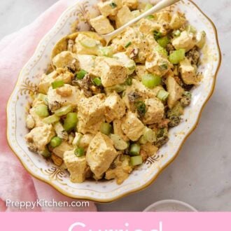 Pinterest graphic of a platter of curried chicken salad with a spoon. A pink napkin beside it.