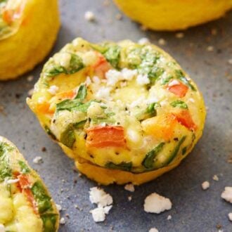 A close up view of egg muffins with feta scattered around.