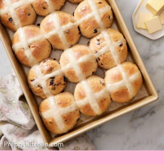 Pinterest graphic of hot cross buns in a baking dish. Plate of butter on the side.