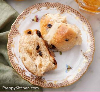 Pinterest graphic of a plate with a hot cross bun torn in half. A platter of more buns and some jam off to the side.