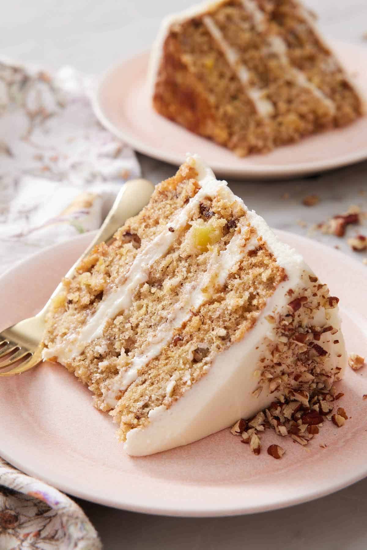 A slice of hummingbird cake on a plate showing the three layers. A second slice in the background.